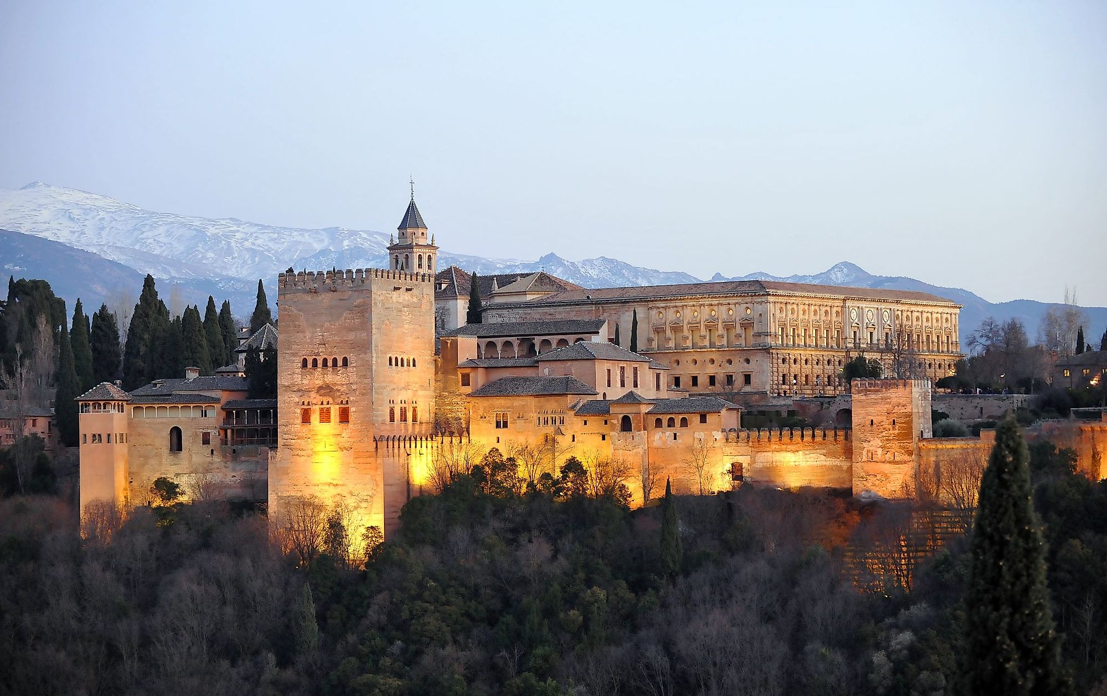 The Palace of Alhambra with Comares Tower, Palace of Charles V and Sierra Nevada at the background during sunset in Granada, Andalusia, Spain.