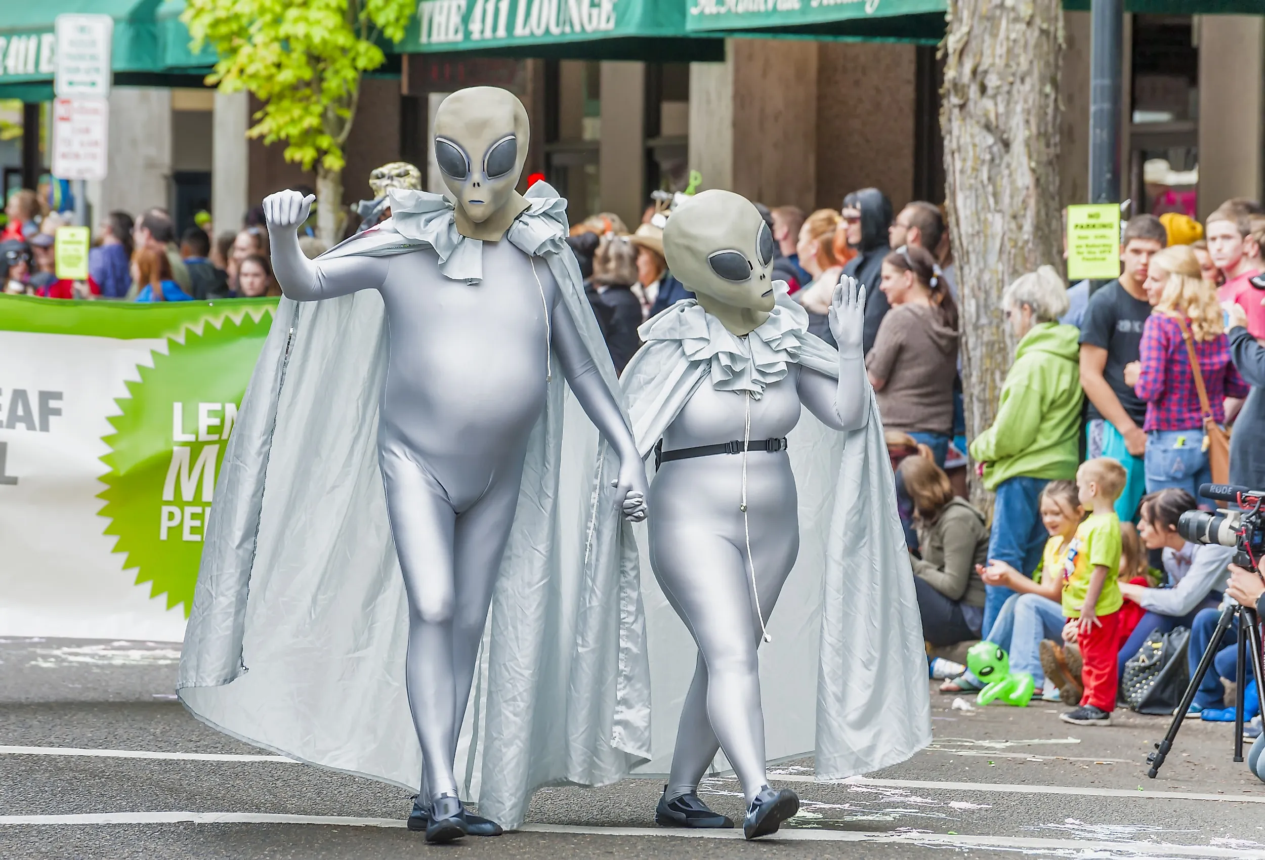 A couple wearing silver alien costumes walk down the street in McMinnville, Oregon. Image credit Dee Browning via Shutterstock
