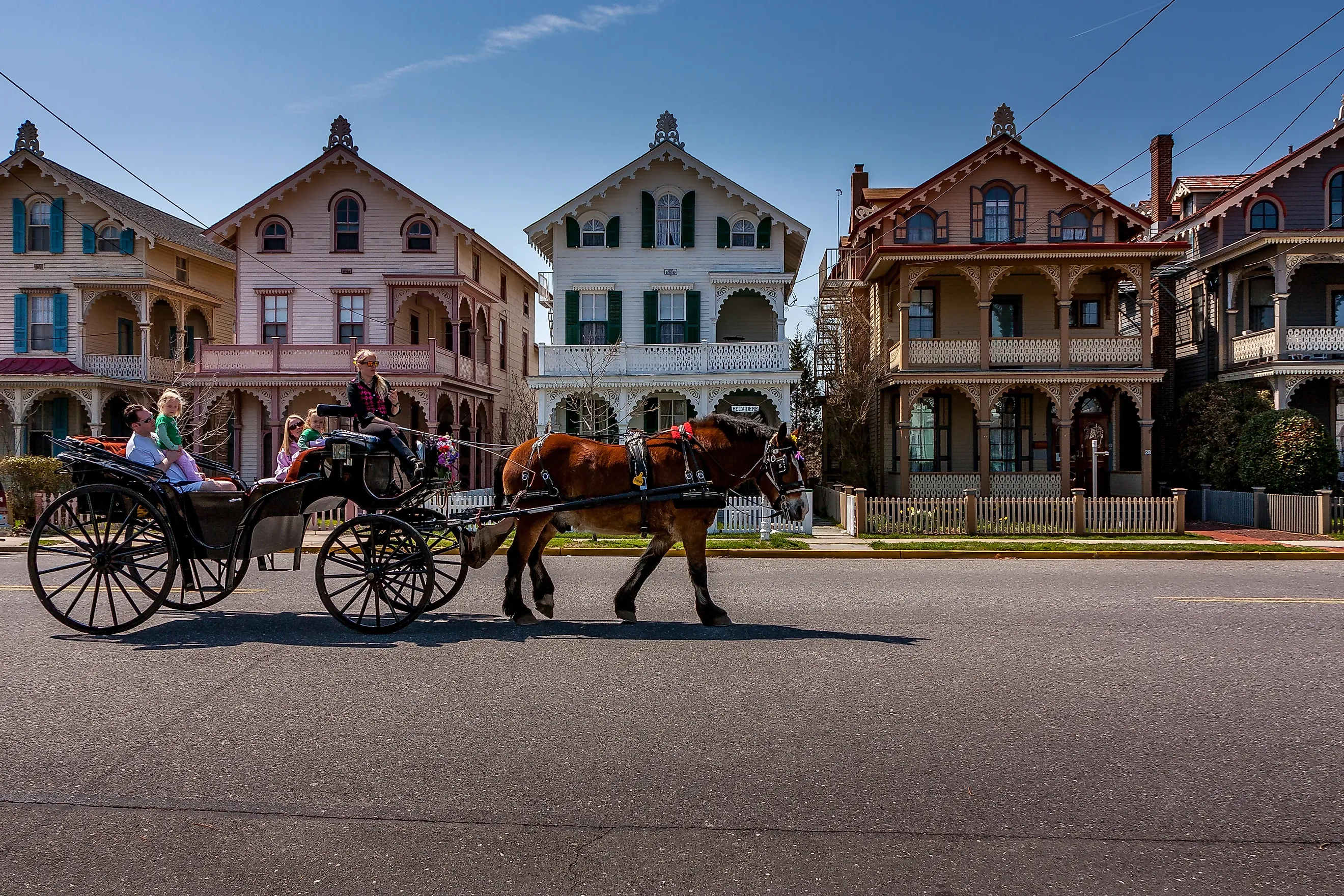 A horse-drawn carriage passes tourists by a row of ornate Victorian gingerbread houses in Cape May, New Jersey. Editorial credit: Steve Rosenbach / Shutterstock.com