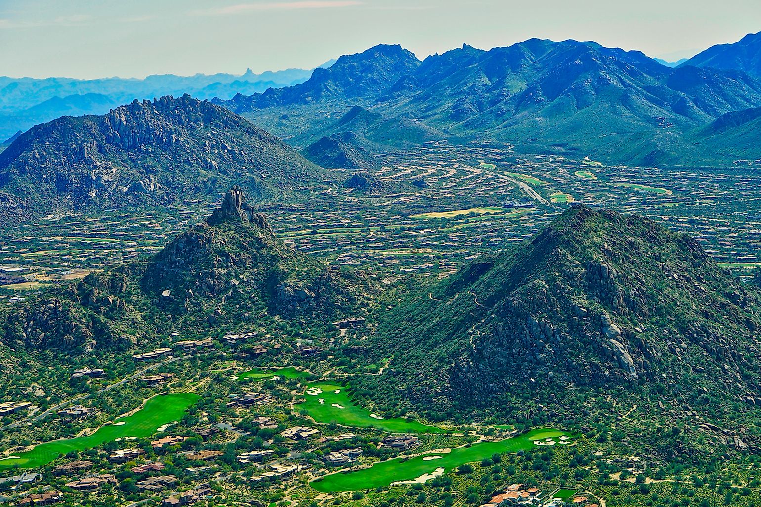 Aerial view of Pinnacle Peak, McDowell Sonoran Preserve, multiple Troon Golf course fairways, and overhead views of residential neighborhoods in Troon Village in Scottsdale, Arizona USA. Image credit: Jessica.kirsh/Shutterstock.com