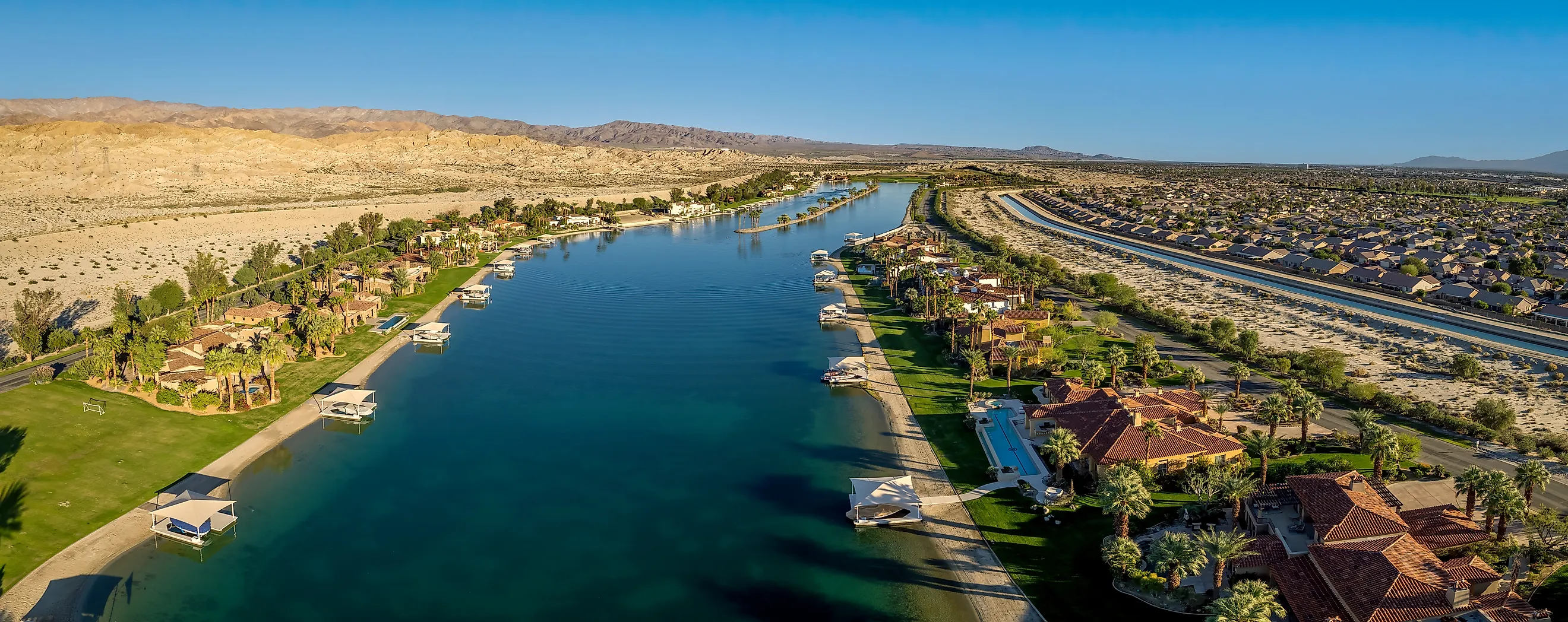 Aerial view of a private lake with waterfront homes and boat docks in a gated Coachella Valley community