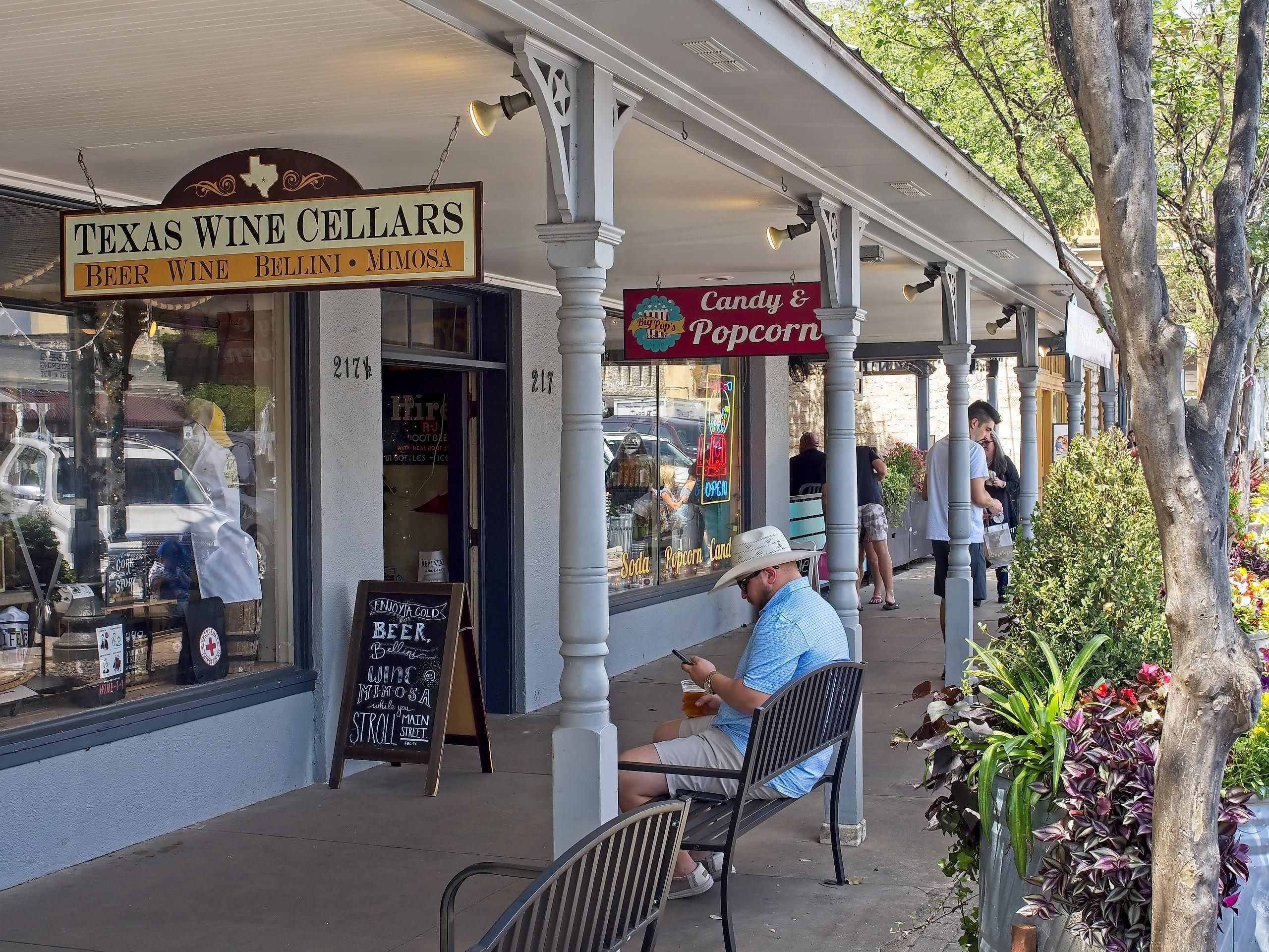 Fredericksburg, Texas. Downtown Fredericksburg Texas along main street. Adult male visitor rests along sidewalk outside wine cellar.