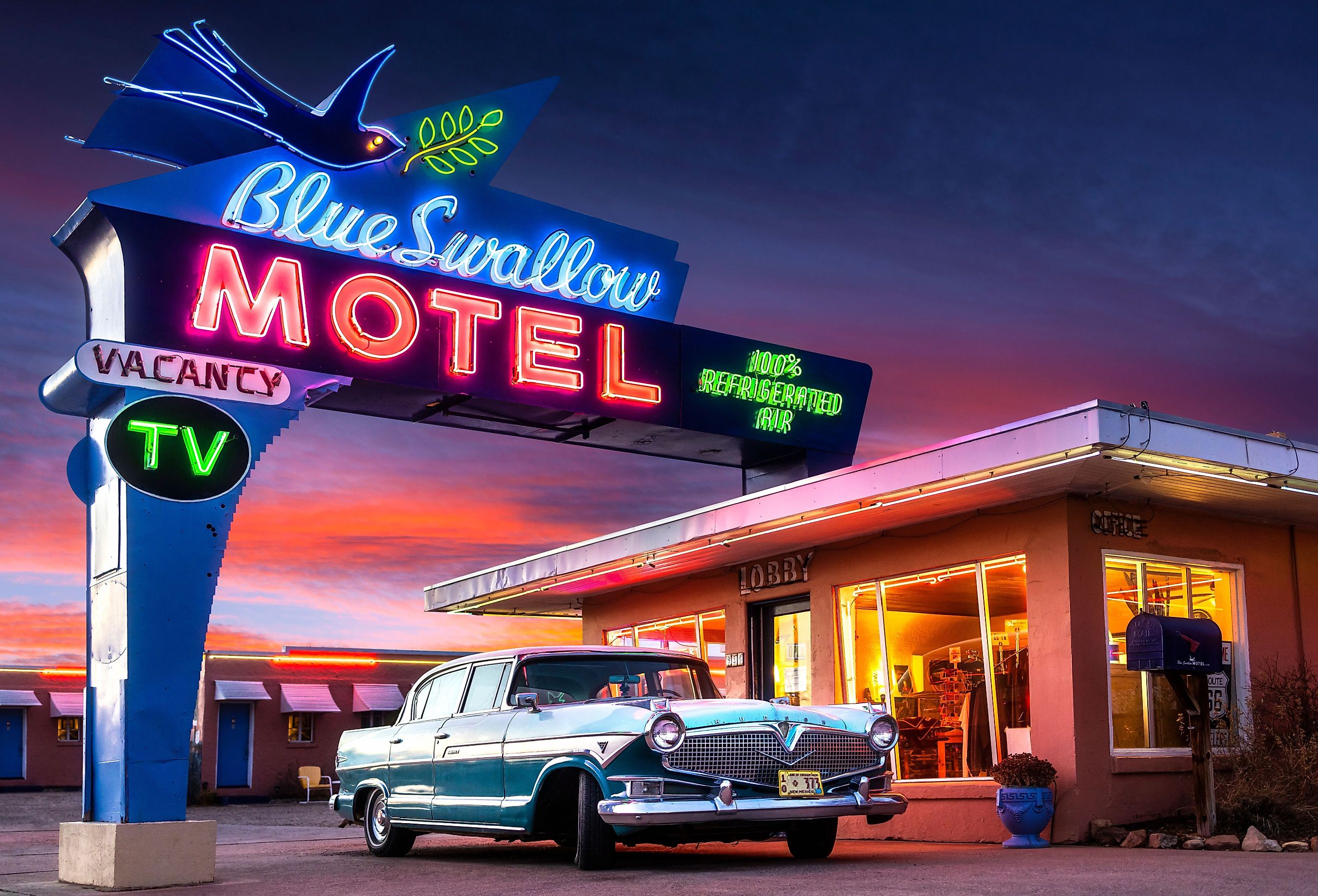 Historic Blue Swallow Motel on Route 66 with neon and classic car at sunset in Tucumcari via Shutterstock.