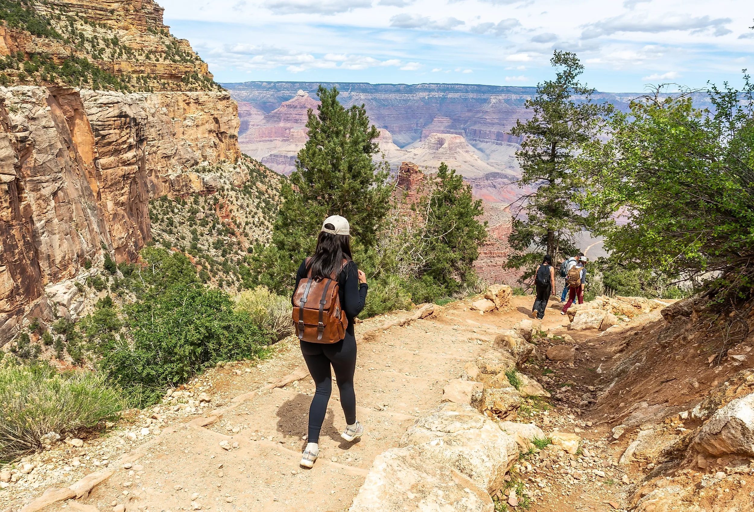 Woman with a backpack hiking down the bright angel trail at Grand Canyon National Park.