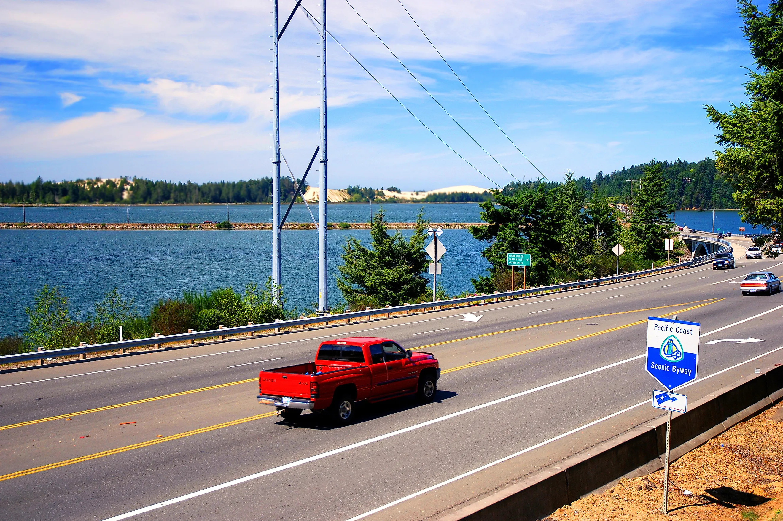 Car drives on Highway 101 with a Pacific Coast Scenic Byway sign in the foreground, Editorial credit: Karin Hildebrand Lau / Shutterstock.com