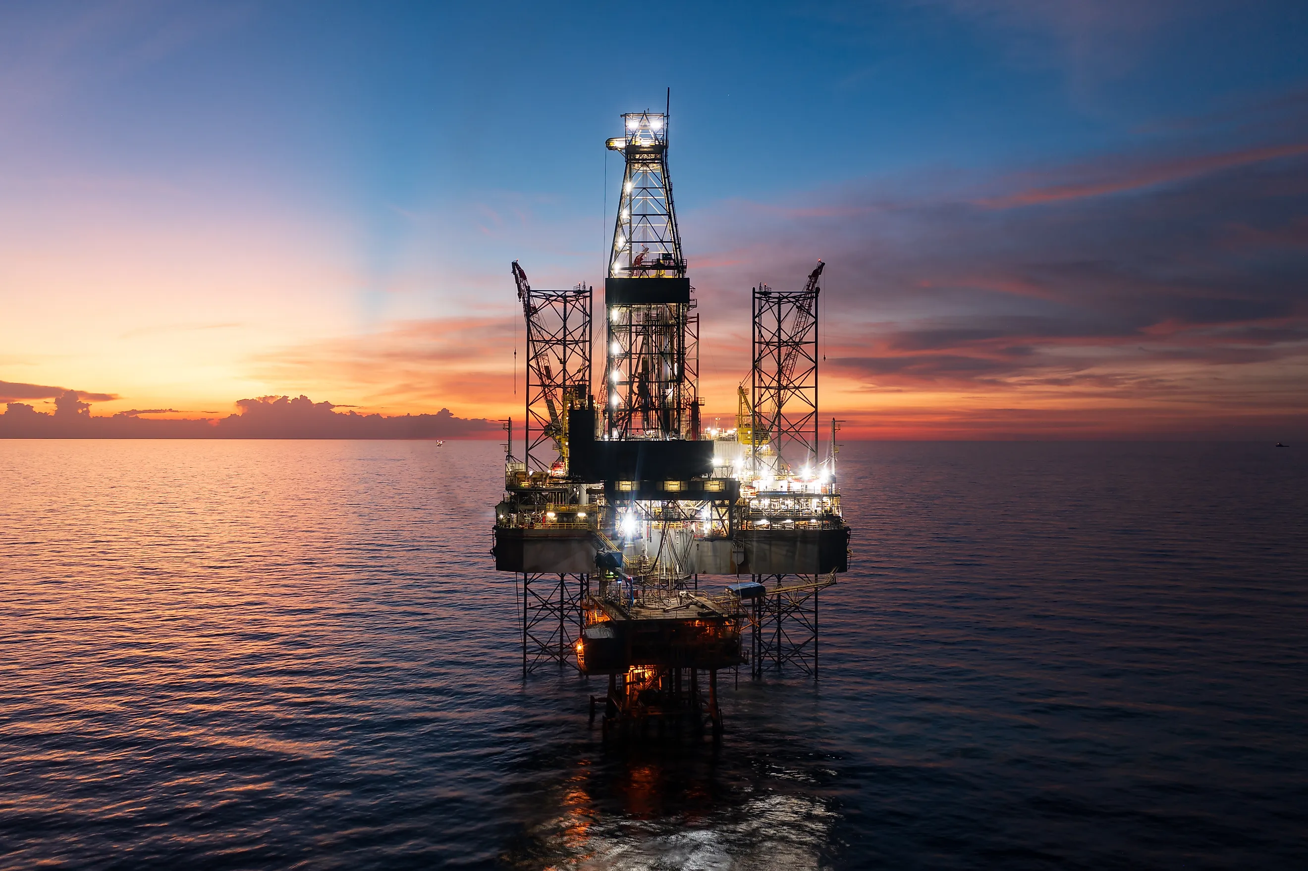 Aerial view of offshore jack up rig and offshore platform during sunset for oil and gas exploration and production.