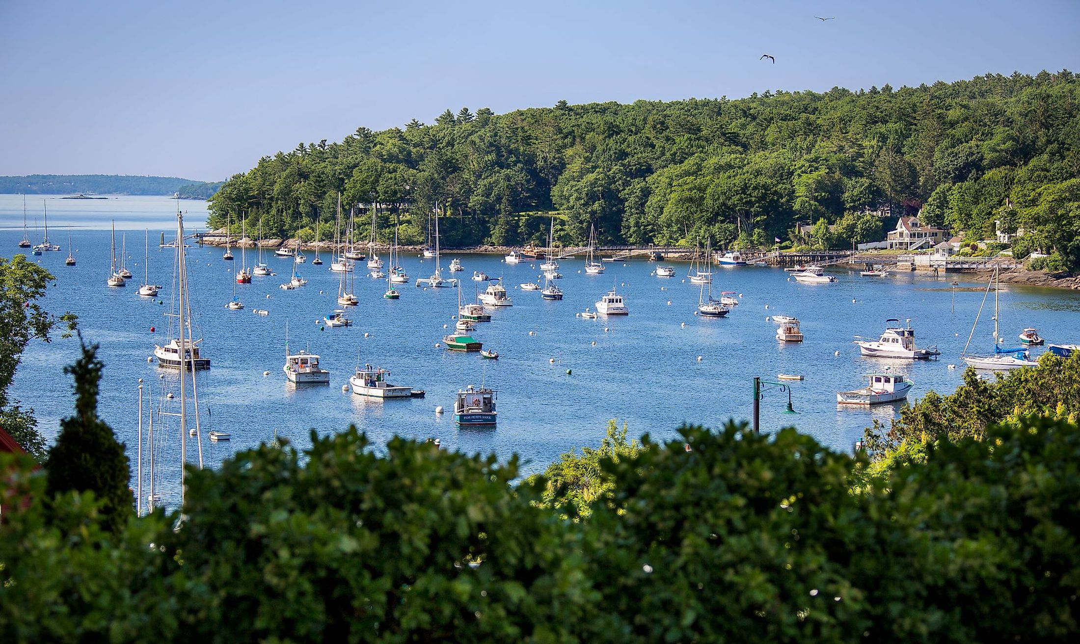 Sailboats and motorboats rest at anchor in Rockport Harbor, Maine, on a beautiful summer day. Editorial credit: James Dalrymple / Shutterstock.com