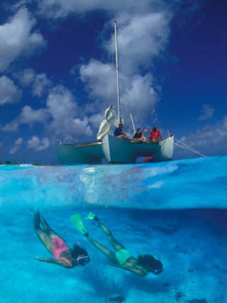 Female Divers Submerged Below Catamaran