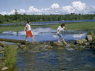 Barefoot Women Cross Rocks in Narrow Mississippi River at its Source