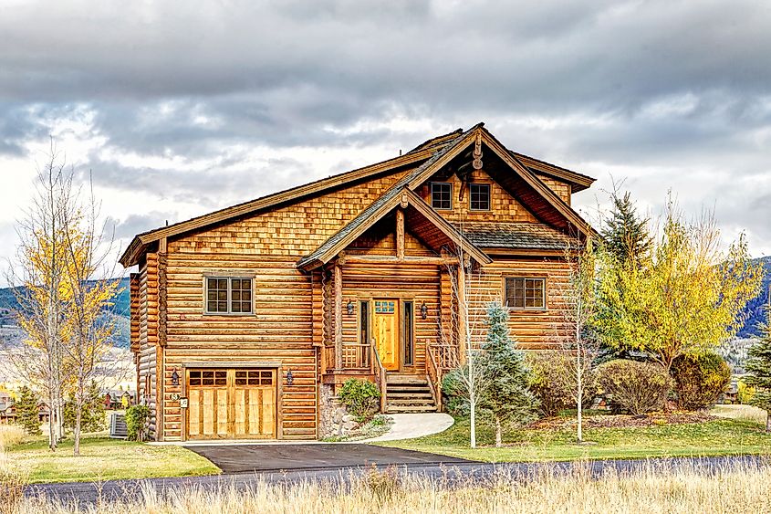 The exterior of a rustic log cabin, nestled at the base of the majestic Teton mountain range in Driggs, Idaho