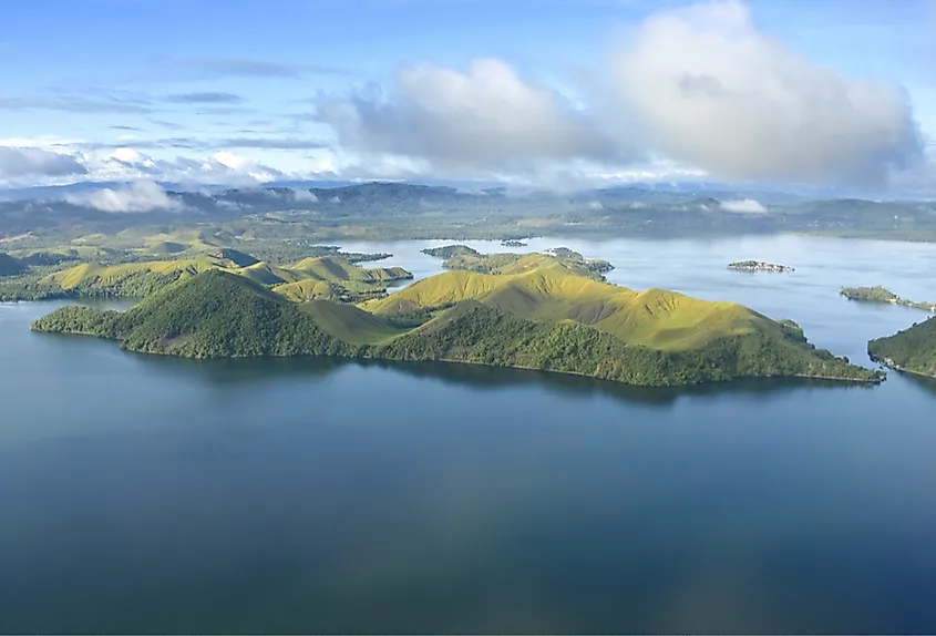 An aerial photo capturing the coast of New Guinea, showcasing the lush jungles and areas affected by deforestation.