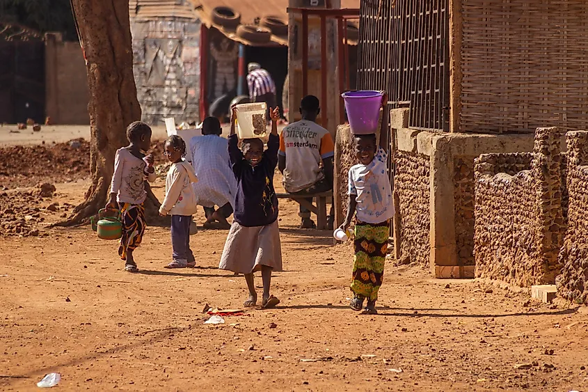 Young girls carrying buckets with water on their heads in Sankandi, The Gambia